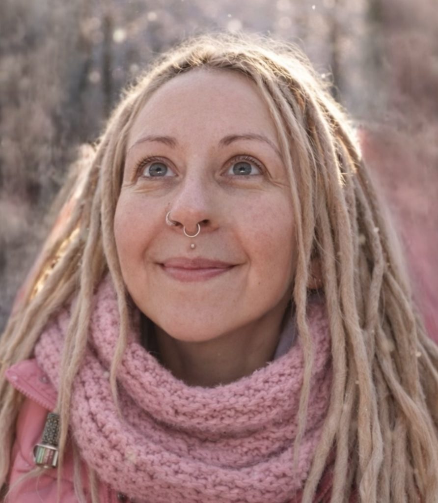 Frau mit blonden Dreadlocks schaut in den Himmel